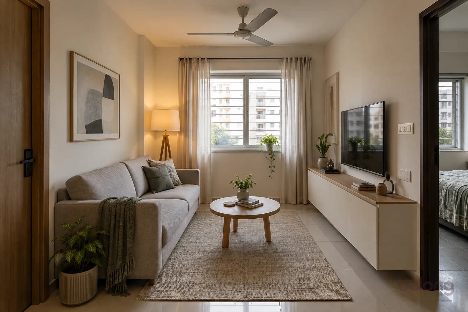 A compact living room with a greige sofa, a round oak table and a long, shallow white storage cabinet.