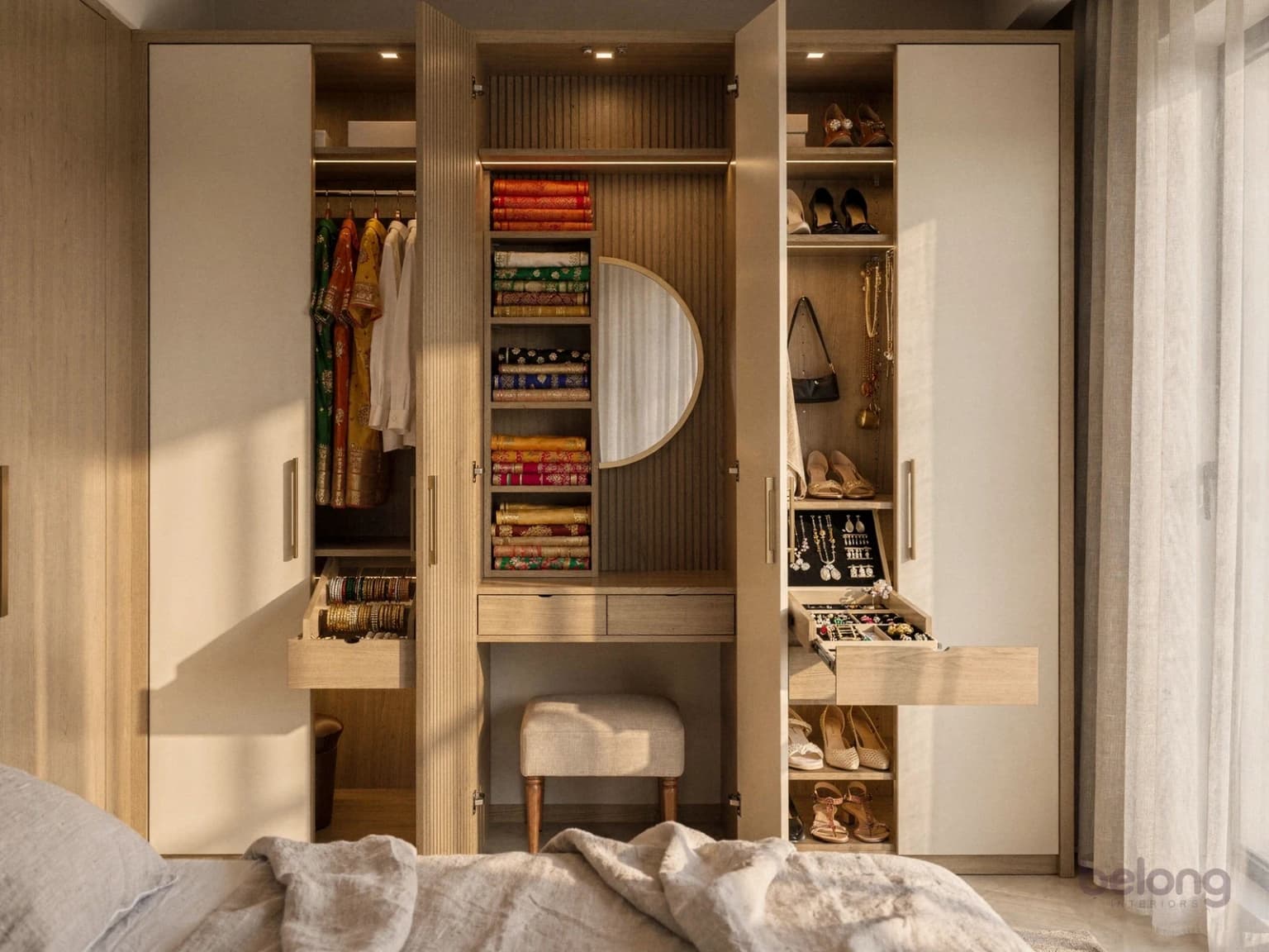 Fluted oak wardrobe wall with lit shelves of folded sarees, shoes and a dressing nook
