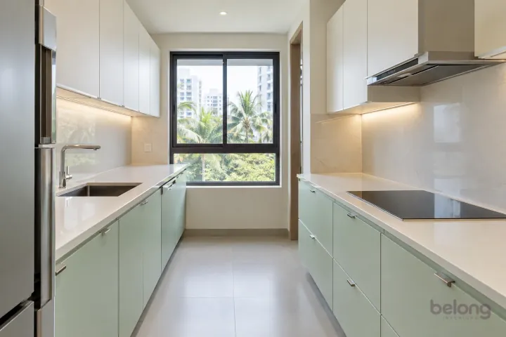 Compact parallel kitchen with pale mint base cabinets, white wall storage and a clear central aisle.
