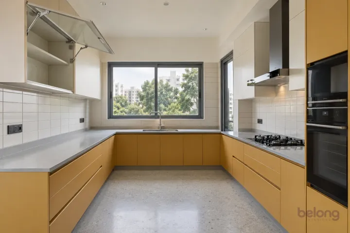 New modern lift-up glass cupboard in muted saffron and off-white, with pale grey quartz worktops and off-white small rectangular ceramic tiles.