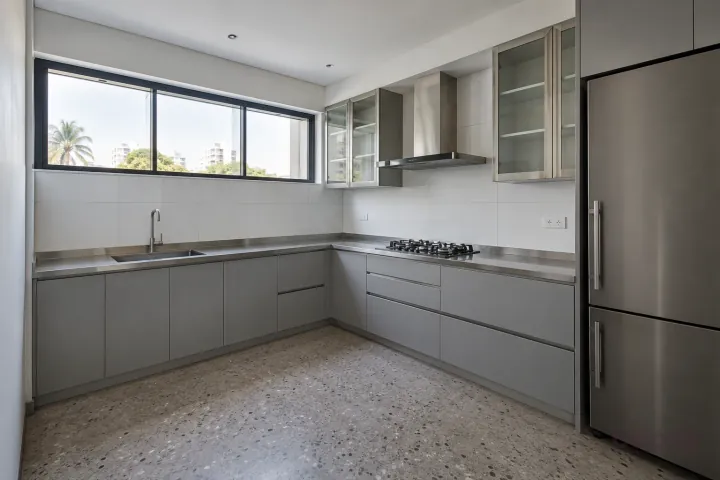 New modern compact L-shaped kitchen in silver grey and stainless steel, with satin stainless steel worktops and large white porcelain tiles.