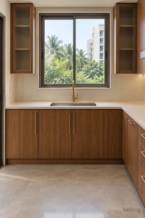 Teak sink arm under a wide window, with teak veneer and cream quartz finishes, precise fitted joinery and pristine surfaces in a contemporary Indian home.