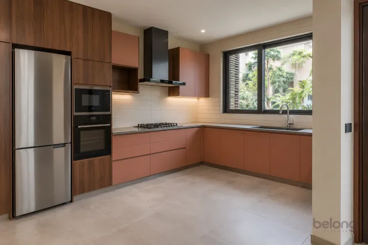 New modern compact L-shaped kitchen in dusty coral and walnut, with warm grey quartz worktops and ivory horizontal stacked porcelain tiles.