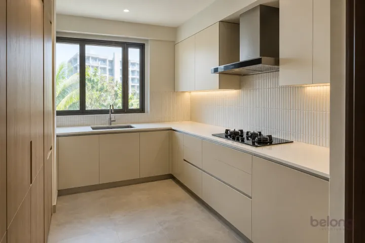 Compact ivory L-shaped kitchen with vertical finger tiles, pale oak cabinets and quartz worktops.