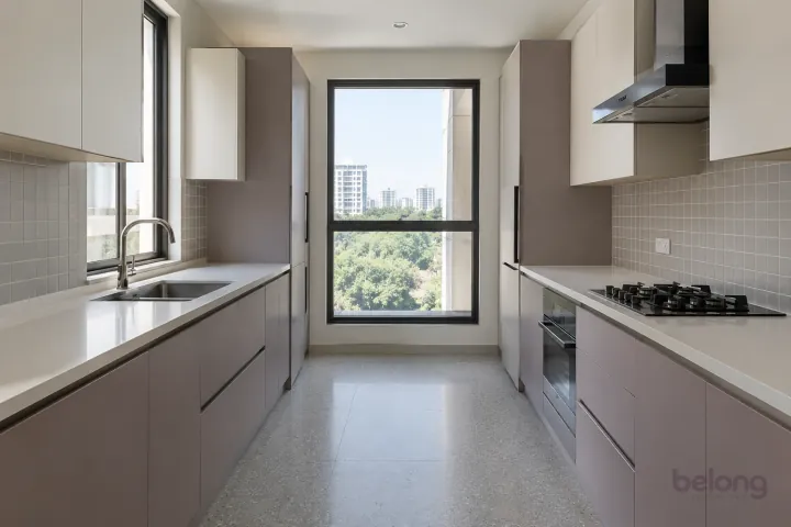New modern parallel kitchen with a clear aisle in lilac grey and warm white, with plain white quartz worktops and soft grey satin square tiles.