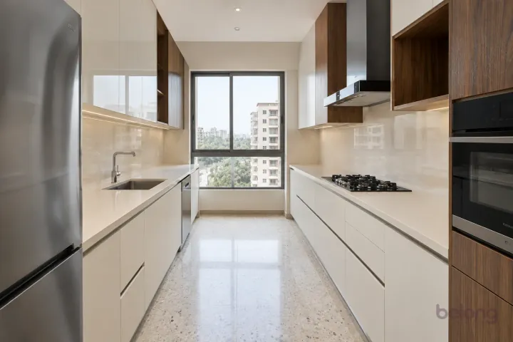 New modern parallel kitchen with a clear aisle in warm white and figured walnut, with plain warm-white quartz worktops and ivory large-format porcelain.