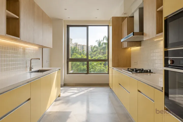 New modern parallel kitchen with a clear aisle in butter yellow and natural oak, with cream sintered stone worktops and warm-white small square tiles.