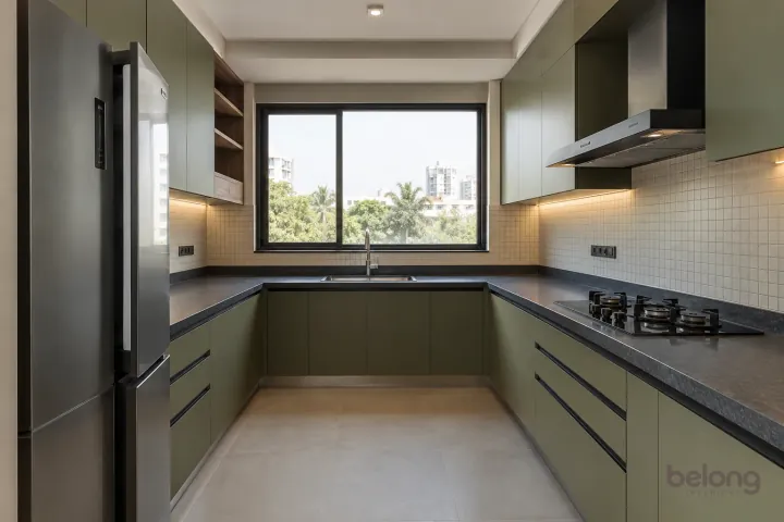 New modern generous U-shaped kitchen in olive and charcoal, with honed charcoal quartz worktops and cream micro-grid ceramic tiles.