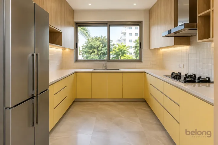 New modern generous U-shaped kitchen in butter yellow and natural oak, with cream sintered stone worktops and warm-white small square tiles.