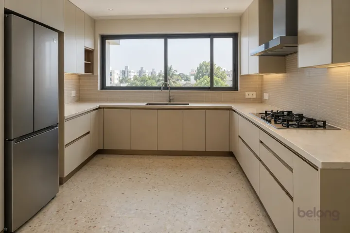 New modern generous U-shaped kitchen in oatmeal and brushed bronze, with warm ivory sintered stone worktops and slim horizontal oatmeal ceramic tiles.