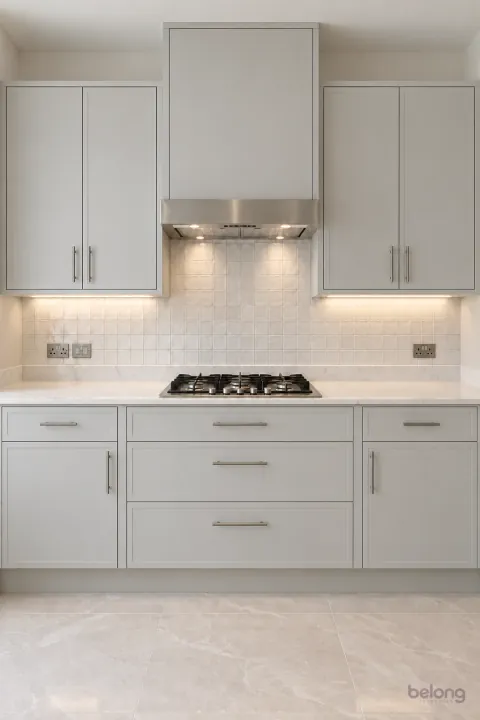 Pale-grey slim-frame kitchen with glazed tiles, with pale grey and marble-look quartz finishes, precise fitted joinery and pristine surfaces in a contemporary Indian home.