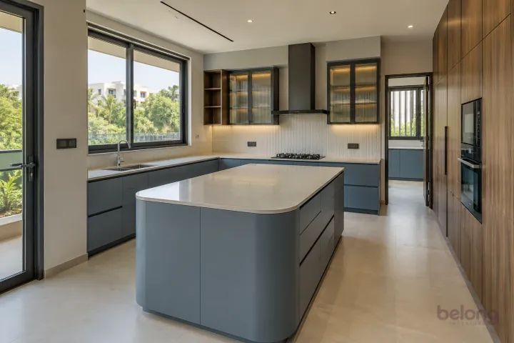 New modern villa kitchen with a central island in blue grey and warm walnut, with ivory quartzite-look porcelain worktops and warm-white vertical stacked ceramic tiles.