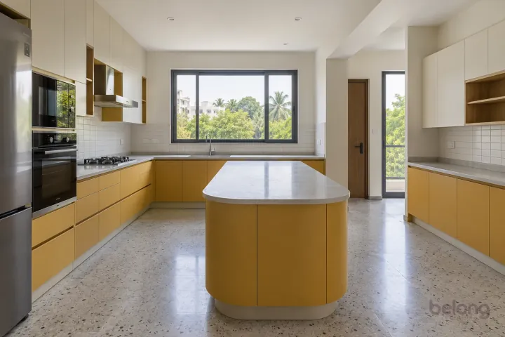 New modern villa kitchen with a central island in muted saffron and off-white, with pale grey quartz worktops and off-white small rectangular ceramic tiles.