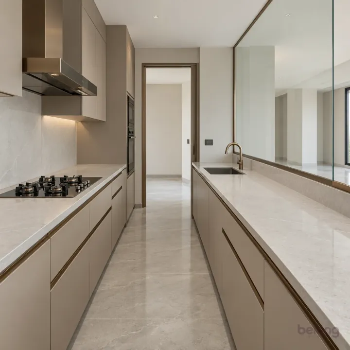 Greige galley with a fitted glass screen, with greige and pale grey quartz finishes, precise fitted joinery and pristine surfaces in a contemporary Indian home.