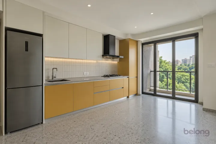 New modern compact straight kitchen in muted saffron and off-white, with pale grey quartz worktops and off-white small rectangular ceramic tiles.