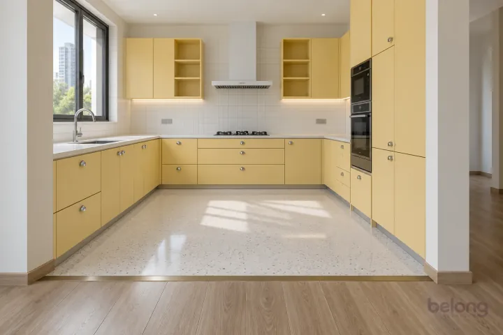 Butter yellow U-shape zoned by terrazzo floor, with butter yellow and white terrazzo finishes, precise fitted joinery and pristine surfaces in a contemporary Indian home.