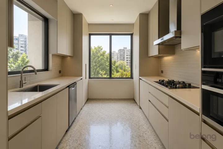 New modern parallel kitchen with a clear aisle in oatmeal and brushed bronze, with warm ivory sintered stone worktops and slim horizontal oatmeal ceramic tiles.