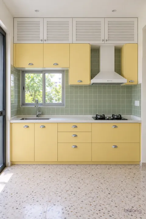 Butter yellow cabinets with a sage tile splash, with butter yellow and sage tile finishes, precise fitted joinery and pristine surfaces in a contemporary Indian home.