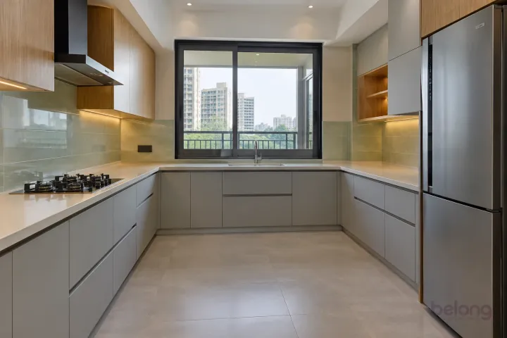 New modern generous U-shaped kitchen in mist grey and light oak, with pale cream quartz worktops and large-format pale sage ceramic tiles.