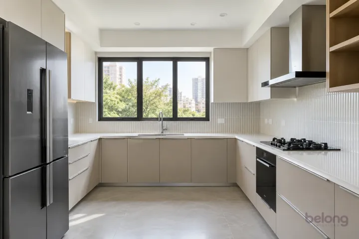 New modern generous U-shaped kitchen in champagne and oyster, with white fine-grain quartz worktops and pearl white narrow fluted ceramic tiles.
