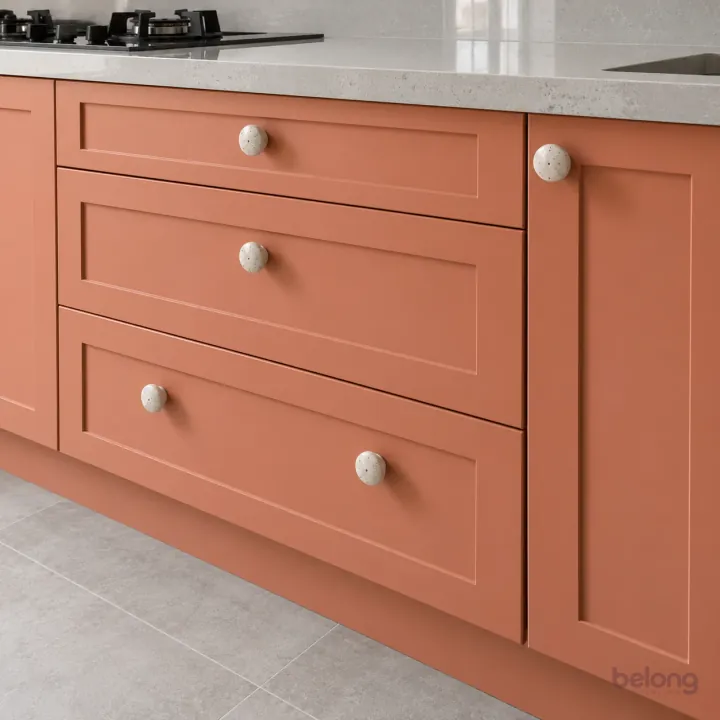 Coral shaker drawers with ceramic knobs, with coral and pale grey quartz finishes, precise fitted joinery and pristine surfaces in a contemporary Indian home.