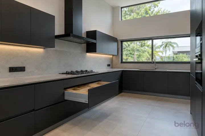 New modern deep drawers with oak organisers in matte black and slate, with honed grey porcelain worktops and pale concrete-look slab backsplash.