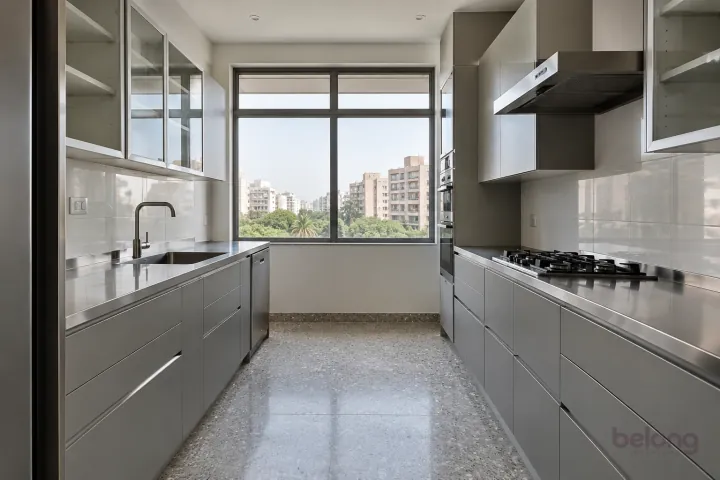 New modern parallel kitchen with a clear aisle in silver grey and stainless steel, with satin stainless steel worktops and large white porcelain tiles.