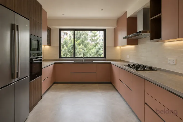 New modern generous U-shaped kitchen in dusty coral and walnut, with warm grey quartz worktops and ivory horizontal stacked porcelain tiles.