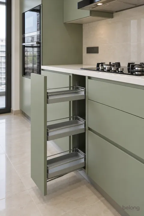 Sage pull-out with empty slim trays, with sage and white quartz finishes, precise fitted joinery and pristine surfaces in a contemporary Indian home.