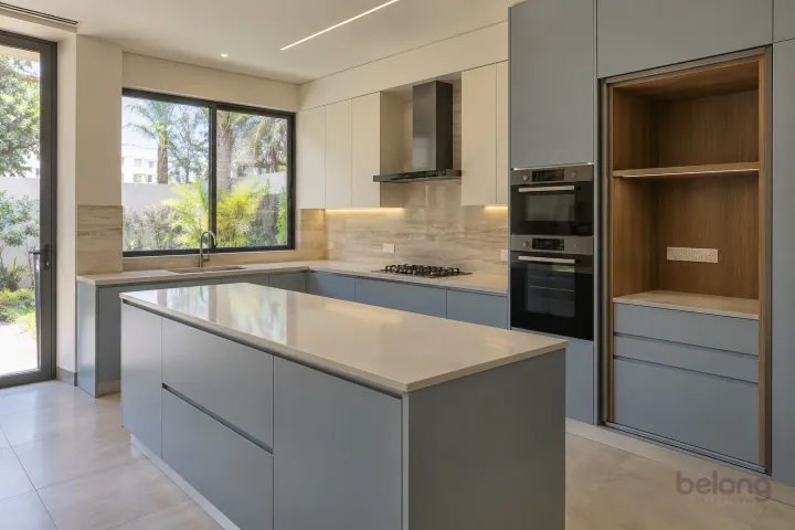 New modern pocket-door appliance garage in dove blue and pale stone, with ivory quartz worktops and travertine-look porcelain slab.