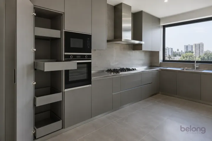 New modern tall pantry with individual trays in concrete grey and satin steel, with brushed stainless steel worktops and warm grey large-format porcelain.