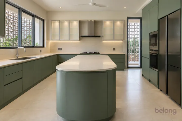 New modern villa kitchen with a central island in eucalyptus green and ivory glass, with cream quartz worktops and pale ivory horizontal ceramic rectangles.