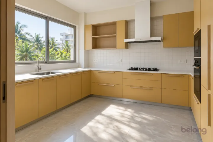 Ochre kitchen around a wide sink window, with soft ochre and white quartz finishes, precise fitted joinery and pristine surfaces in a contemporary Indian home.