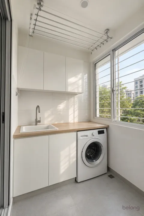White wash area with a ceiling pulley airer, with clean white and pale oak finishes, precise fitted joinery and pristine surfaces in a contemporary Indian home.