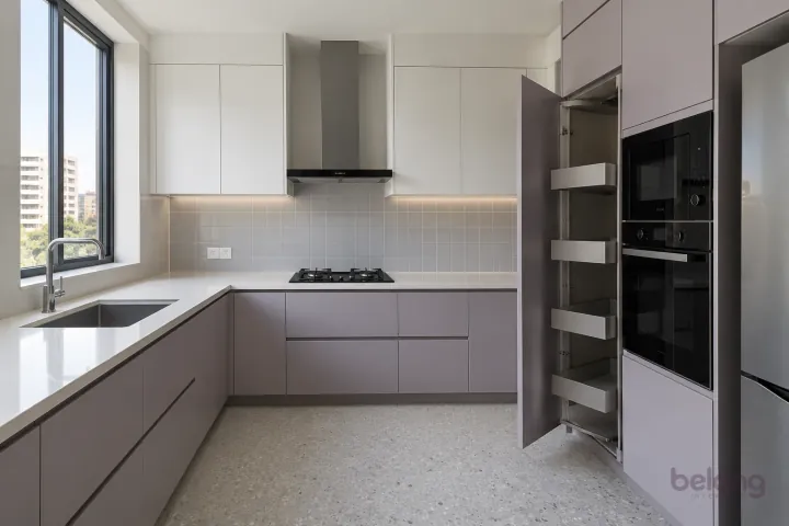 New modern slim pull-out pantry in lilac grey and warm white, with plain white quartz worktops and soft grey satin square tiles.