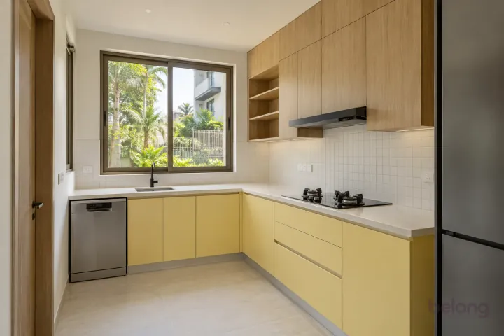 New modern compact sink beside a slimline dishwasher in butter yellow and natural oak, with cream sintered stone worktops and warm-white small square tiles.