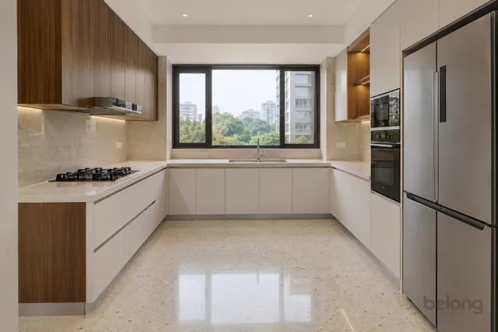 New modern generous U-shaped kitchen in warm white and figured walnut, with plain warm-white quartz worktops and ivory large-format porcelain.