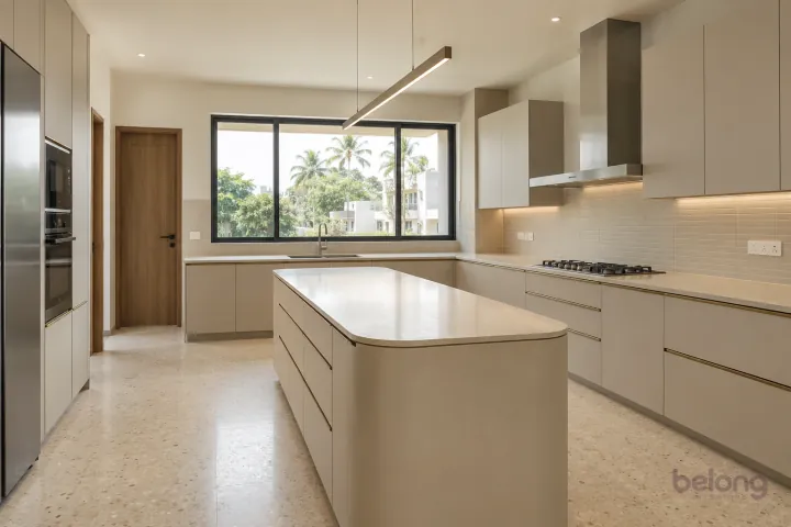 New modern villa kitchen with a central island in oatmeal and brushed bronze, with warm ivory sintered stone worktops and slim horizontal oatmeal ceramic tiles.