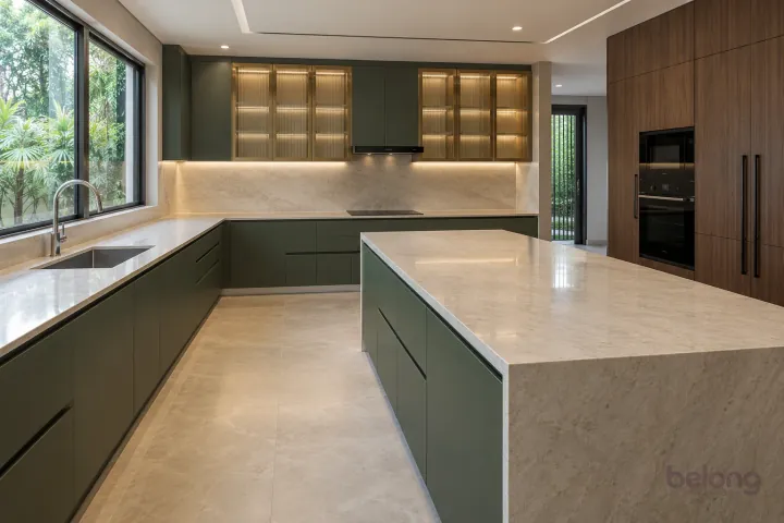 Large forest-green villa kitchen with reeded-glass wall cabinets and a pale quartzite island.