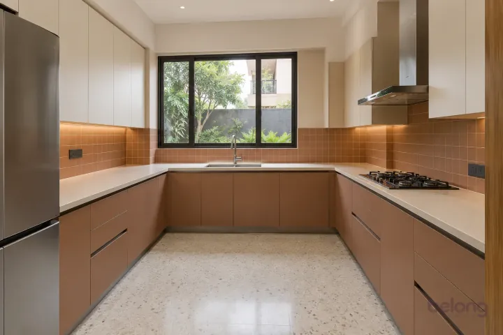 New modern generous U-shaped kitchen in clay and sand, with ivory solid surface worktops and small satin terracotta square tiles.